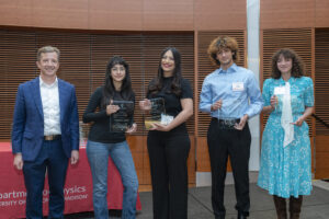 five people stand in a row, four are holding glass plaques