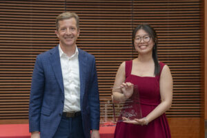 a man and a woman smile, the woman is holding an award