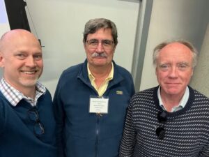 three men pose standing next to each other