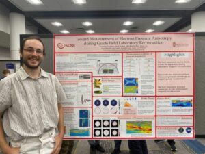 a smiling person stands in front of their scientific poster